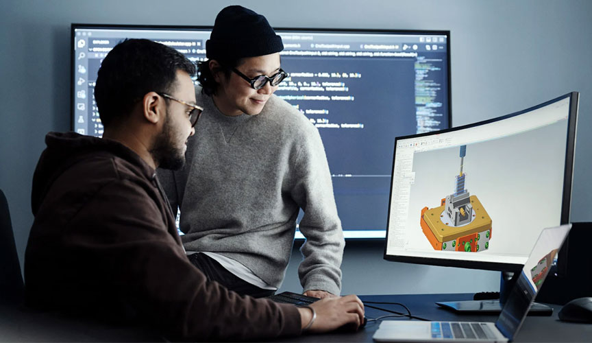 Two people looking at a screen displaying a CAD model of a component. (photo)