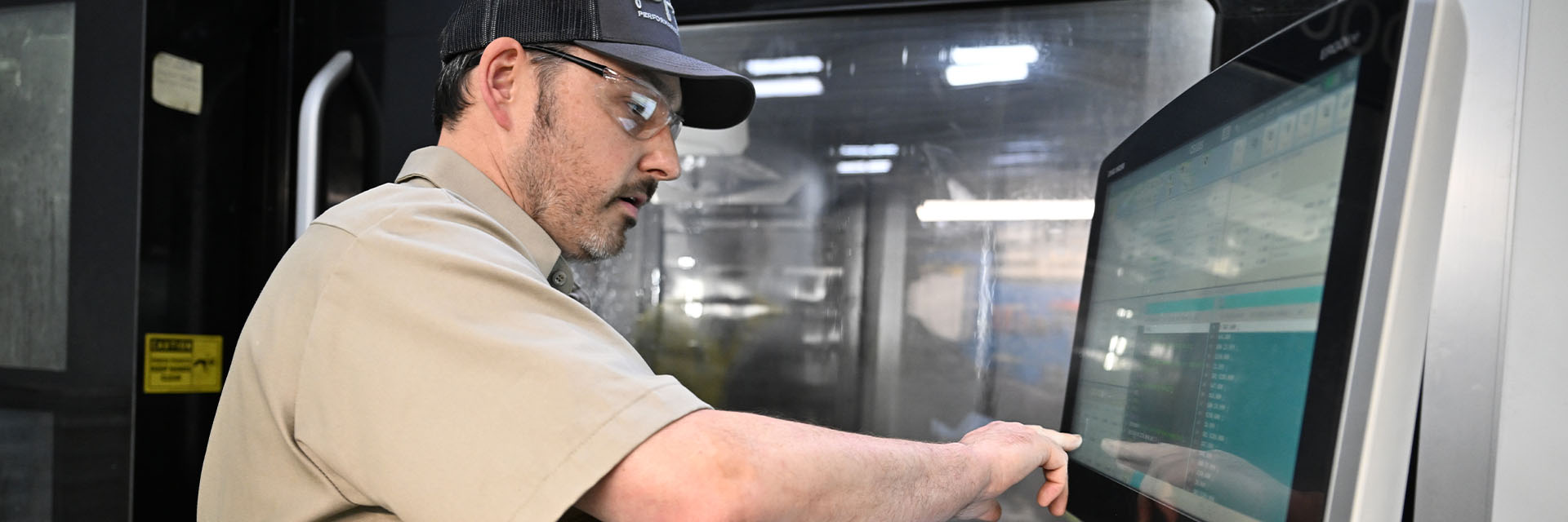 Man operating Sandvik metal-cutting maching using a touch screen (photo)