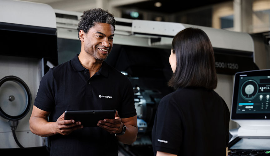 Two employees talking in front of a Sandvik machine