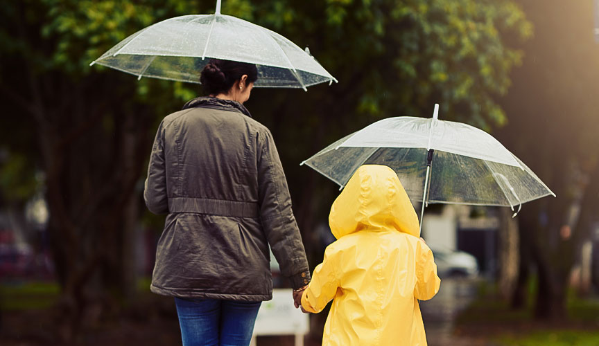 Mother and child with umbrellas crossing a road (photo)